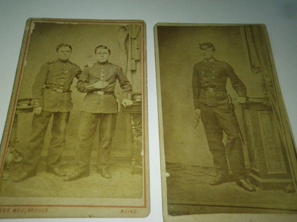 2 Antique Photographs of Soldiers: One photograph shows two soldiers together men appear to be twins, the other photo is of a soldier, he is holding something in his hand possibly a pipe. Measures about 2 1/2" x 4".