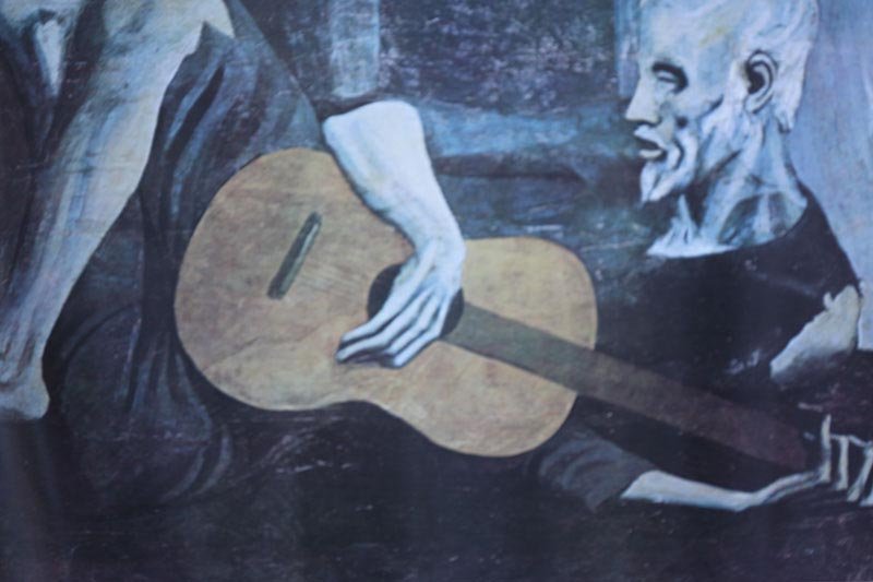 ART POSTER BY PABLO PICASSO: ART POSTER BY PABLO PICASSO **|**|** 24X36 INCHES; UNFRAMED; This poster is of Old Guitarist, by Pablo Picasso. It shows an old barefoot man sitting with a guitar in his lap. He is leaning to the side