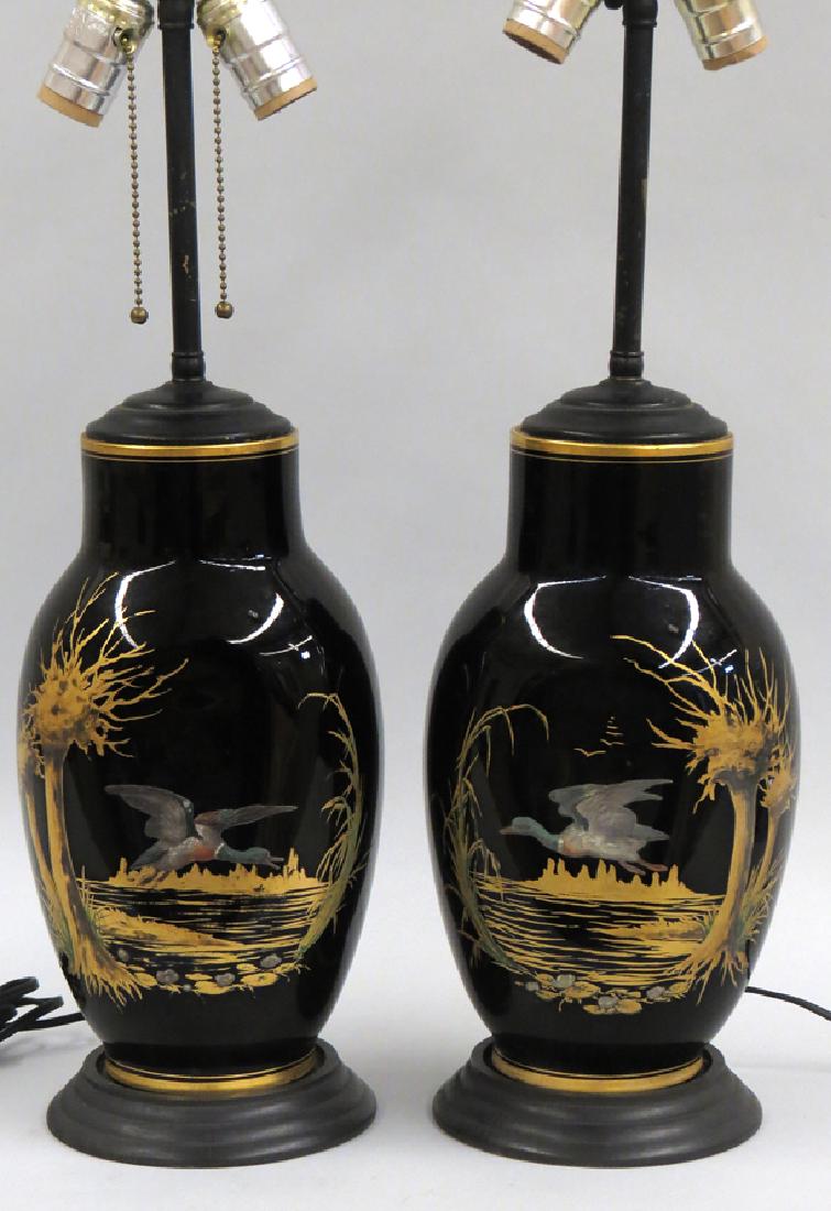 PAIR OF DECORATED BLACK GLASS LAMPS: each painted with a duck flying in gilt-painted swamp landscape, mounted on stepped wood base, 25" total h