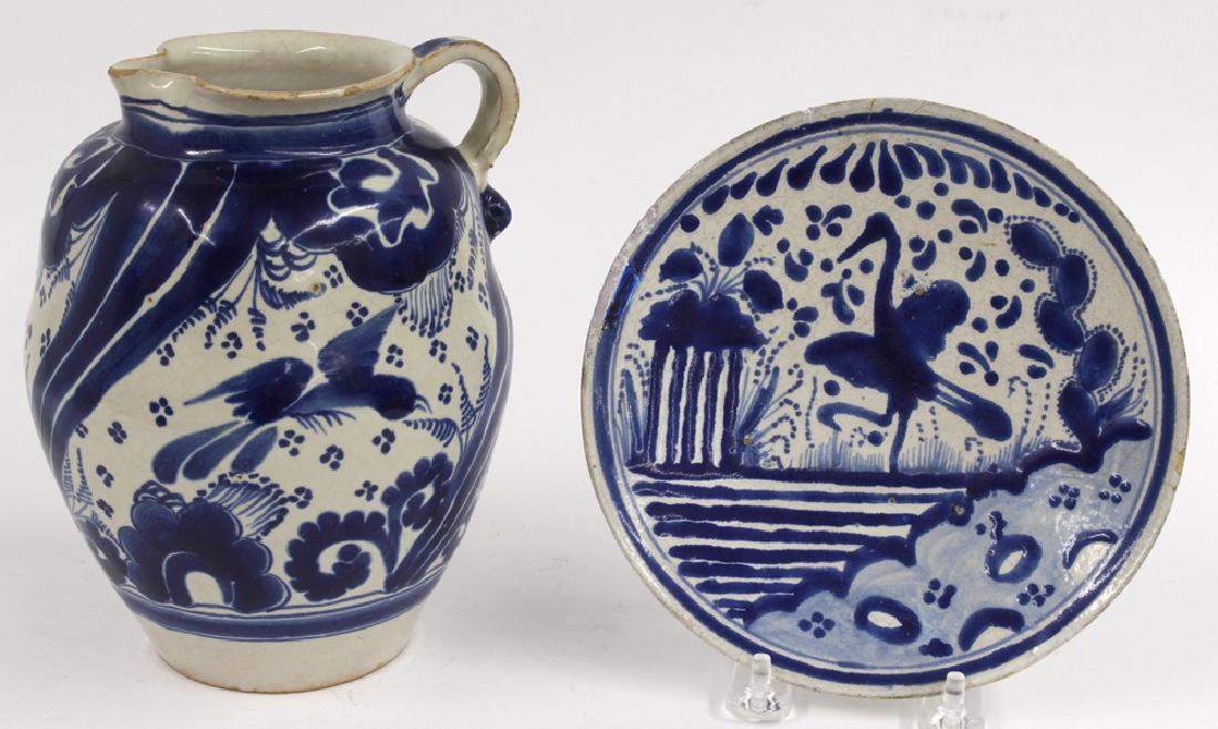 (on 2) TALAVERA POBLANA BLUE AND WHITE EARTHENWARE: c. 1800 or earlier, a tin glazed pitcher with panels of bird and floral decoration, 7.5"h; along with a SMALL DISH decorated with bird in wetlands setting, 7"diam. This type of stylized land