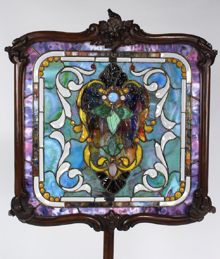 STAINED GLASS AND MAHOGANY FIRE SCREEN: carved frame, pole and tripartite base, screen height adjustable, 50"h; 20"w Estate of Michael C. Moretti, Cranston, Rhode Island