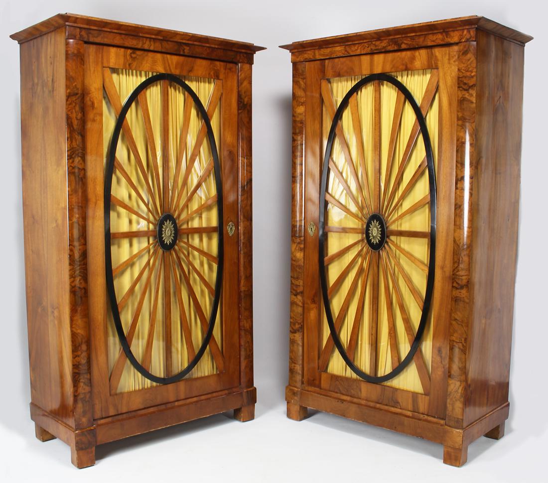 PAIR OF BIEDERMEIER FRUITWOOD TALL CABINETS: c. 1825, each with glazed door with wheel-shaped mullion backed with fan-folded fabric, 67.5"h; 35.5"w; 17.5"d From the home of an Oyster Bay, NY lady moving to smaller quarters. Purcha