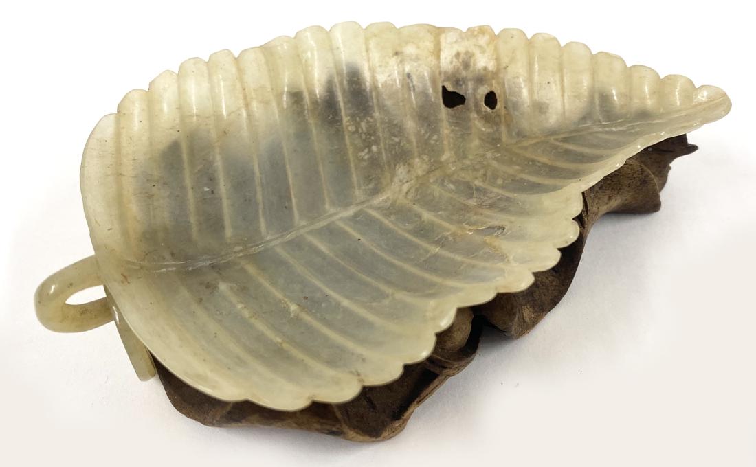 CHINESE CARVED WHITE JADE SCHOLAR: 19th c., thin and delicate leaf-form, on original carved hardwood lotus-form stand, 4.5" by 3"