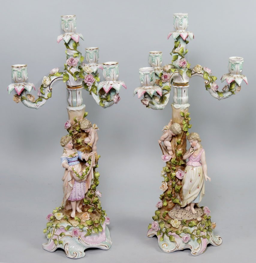PAIR OF SITZENDORF PORCELAIN FIGURAL CANDELABRA: c. 1880, incised Germany 253/7, also crossed blue double-lines mark overall all applied flowers, removable four-light candle-arms, each with country maiden leaning on tree with cherub looking on, 21��