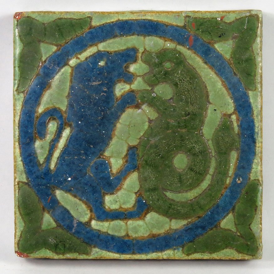 GRUEBY POTTERY TILE: a blue lion joined with a green serpent in blue circle, dark green leaves to each corner, die stamped 677, 6"square, 1"thick