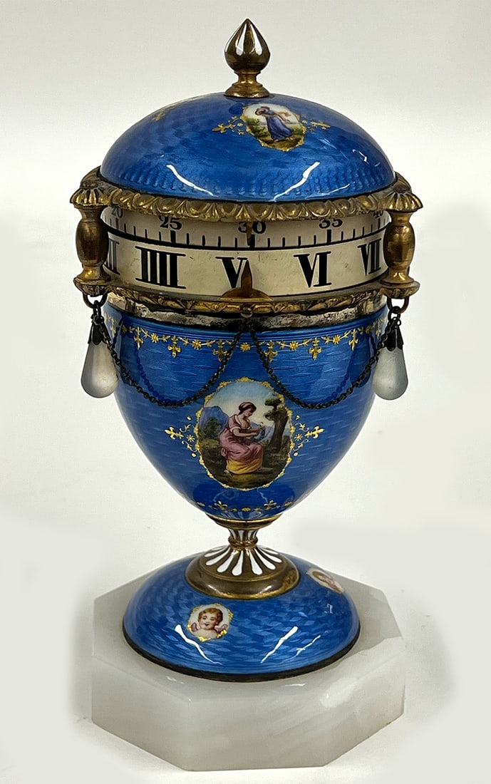 VIENNESE GUILLOCHE BLUE ENAMEL ANNUALAR CLOCK: 19th c., blue enamel with cartouches of women and putti; chain swags with glass drops; time band with Roman numeral hours, minutes numerical; mounted on white marble octagonal base; 7.5:h; 3.5"di