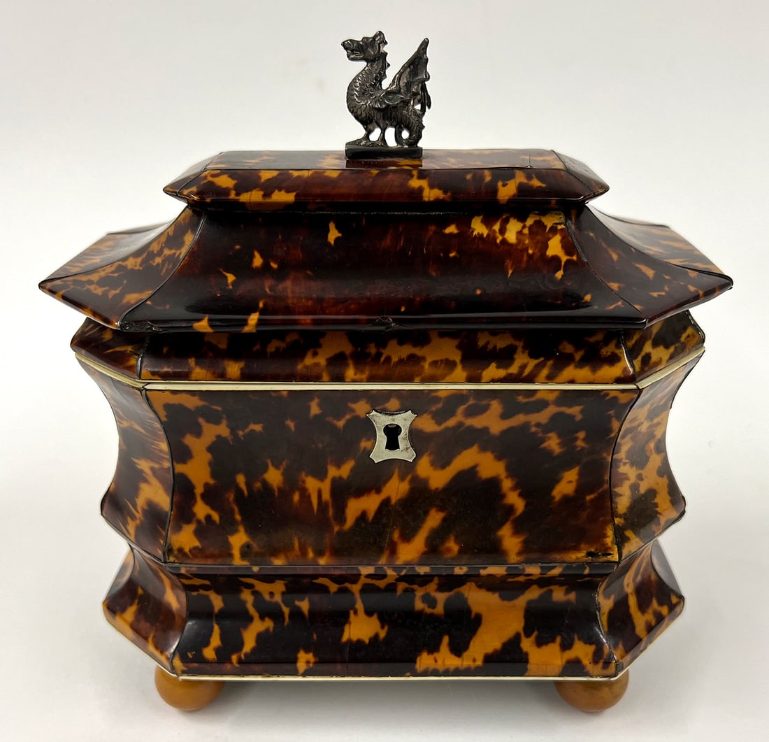 ENGLISH REGENCY DOUBLE TEA CADDY: double-concave form with canted corners; double shell-lidded interior; metal dragon applied to lid; silver escutcheon; wood ball feet; 7.5"h; 6.5"w; 4"d NOTE: Apologies, we cannot appro