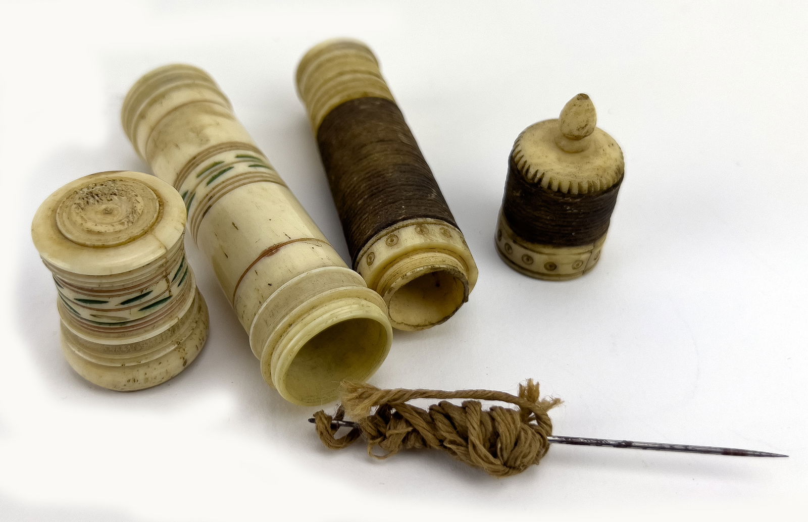 (on 2) NAPOLEONIC PRISONER OF WAR BONE NEEDLE CASES: 18/19th c., one wrapped with brown thread (old needle inside); 4.25"; .75"diam; the other with incised green leaf bands, 4.25'; 1"diam.NOTE: Apologies, we cannot approve bidders during the auction.