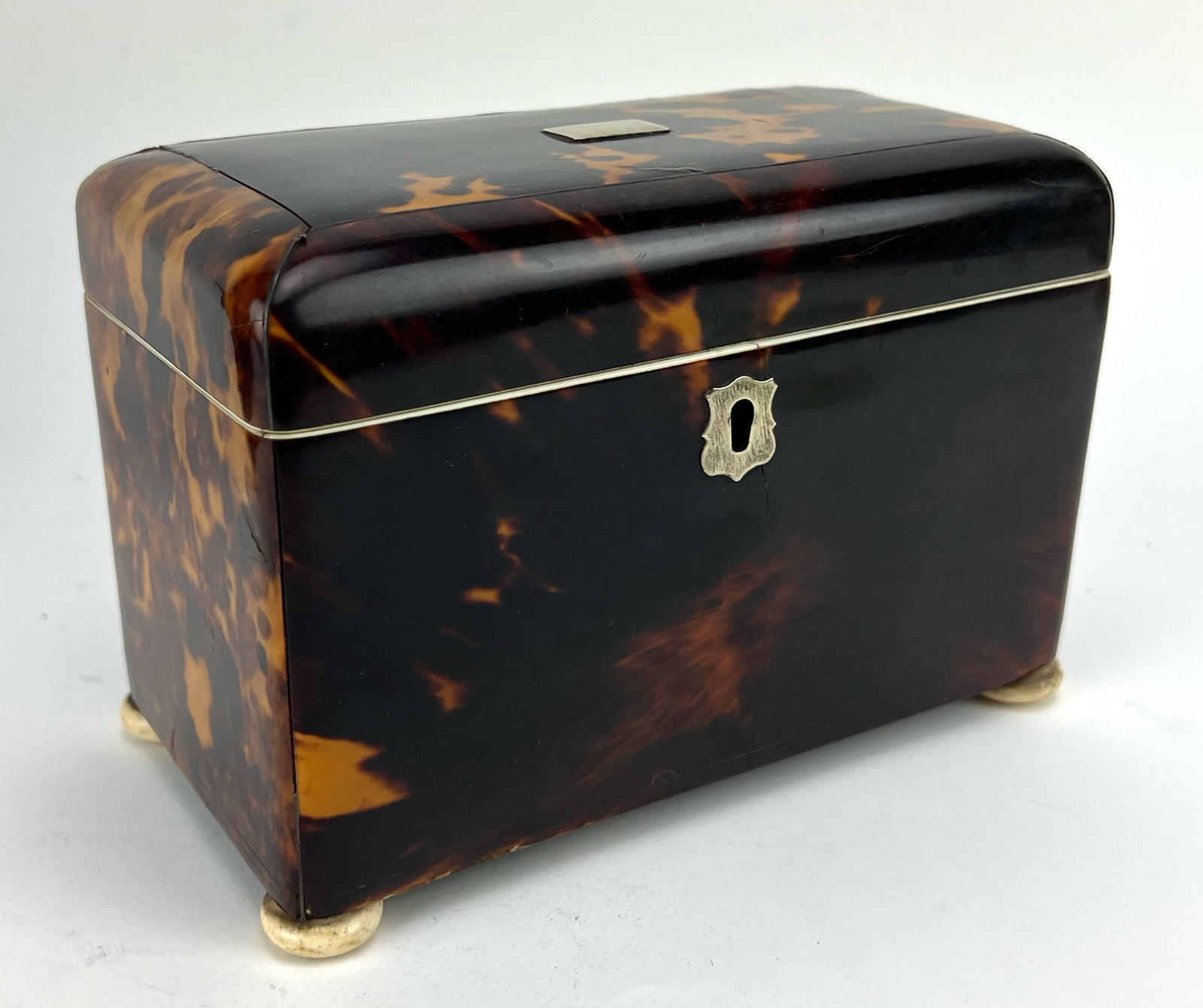 ENGLISH GEORGIAN TORTOISE SHELL TEA CADDY: interior lid handles and lining of body and outer lid rims also bone ; with silver furnishings; bone bun feet; 4.75" h; 6.75"w; 3.75"d NOTE: Apologies, we cannot approve bidders during the auction.