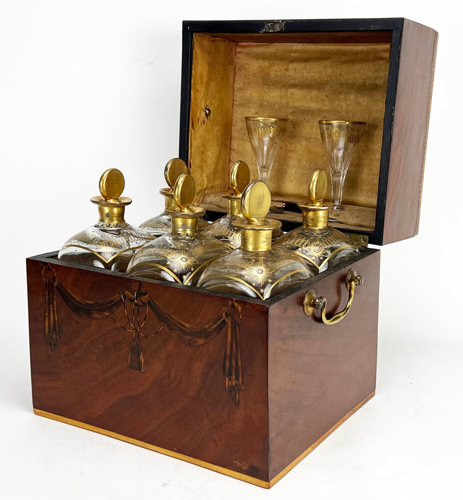 ENGLISH GEORGE III INLAID MAHOGANY DECANTER BOX: c. 1815, fitted with (6) gilt embellished glass bottles and (2) claret glasses; the case decorated with inlaid swag and tassel design to front; hinged lid with satinwood band and checker inlay to edge