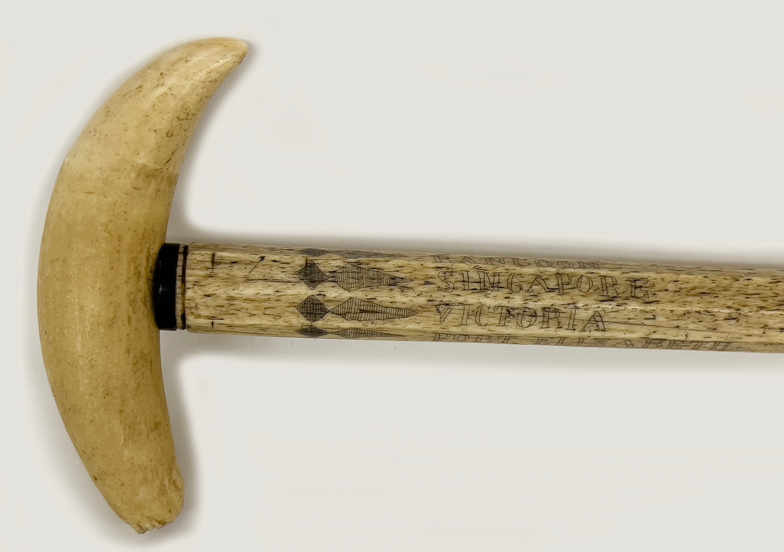 19TH C. SCRIMSHAW WHALE BONE WALKING STICK: whale tooth handle, 5.5"; octagonal shaft with band of geometric scrimshaw and names of ports; PORT L'ORIENT CAPE TOWN; RANGOON; SINGAPORE; VICTORIA; PORT ELIZABETH; ZANZIBAR; CALCUTTA; 38" NOTE: We c