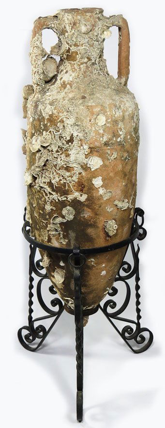 LARGE ANCIENT ROMAN EARTHENWARE AMPHORA: recovered from shipwreck, double handles, encrusted with shells and barnacles; the amphora measures 37”h, mounted in iron stand Brought from the family home in Italy when the mother moved to Provide