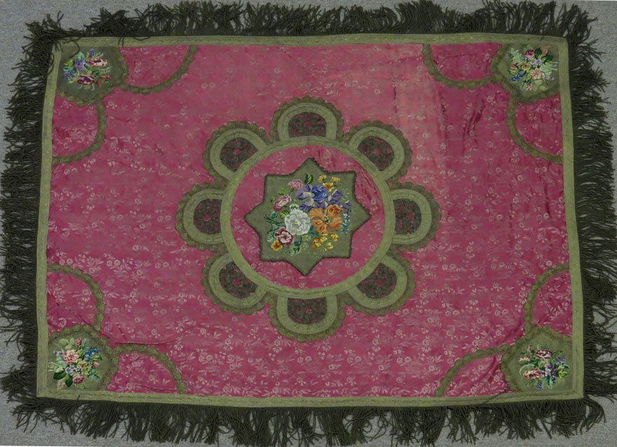 19TH C. TABLE COVER: floral petitpoint center with scalloped metallic border, repeated at each corner, on rose colored silk, long metallic thread fringe, 4’2” x 5’7”