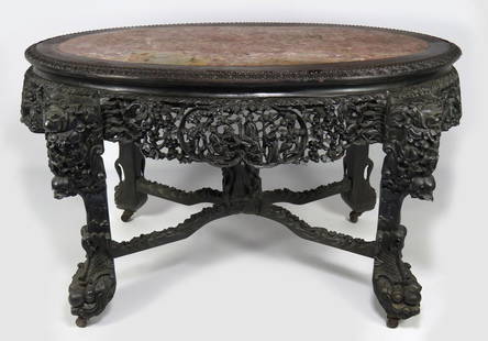 ORNATEY CARVED HARDWOOD CHINESE CENTER TABLE: 19th c., with inset marble top, the pierced apron carved with figures, fruits and florals, the cabriole legs ending in dragon head feet are joined by carved cross stretcher having figural carved finia