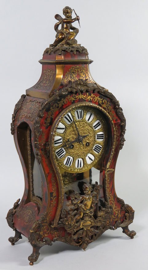 FRENCH BRONZE, BRASS AND BOULLE SHELF CLOCK: 19th c., removable crest with bronze cupid, shaped case with brass inlay and bronze mounts, the glass door with bronze Cupid; cut-out brass dial with porcelain panels of Roman numerals, the interior w