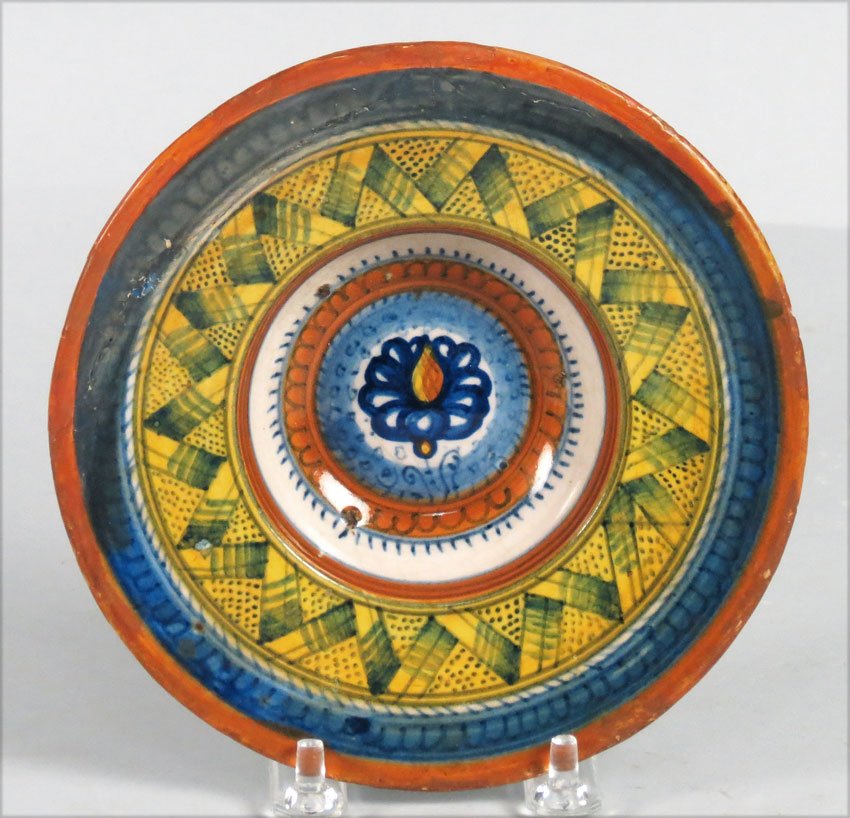 MAIOLICA SMALL PLATE (TONDINO): Faenza, c. 1520 cardinal's hat-form, flower enclosed in a scalloped surround to the well, the rim with band of geometric patterns, the underside with close concentric blue circles; blues, yellow and o