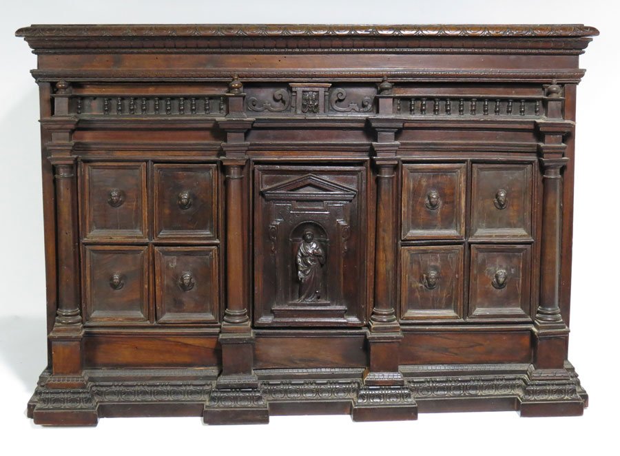 RENAISSANCE CARVED WALNUT TABLE-TOP CABINET: architectural-form, fitted with center cupboard with figural carved door, flanked by two rows of small drawers with carved head pulls, concealed drawers in the architectural elements, 24"h; 35"w; 24"d