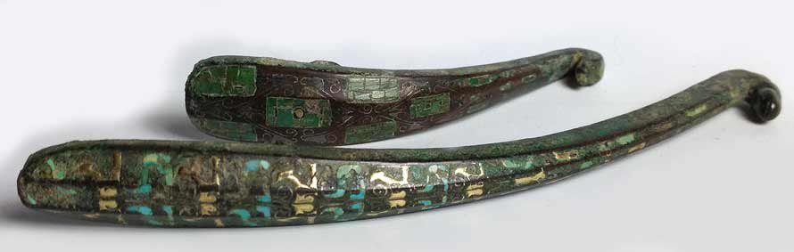 (2) INLAID BRONZE GARMENT HOOKS: Eastern Han, one with gold, silver and turquoise inlay, 7”; the other inlaid filigree and green stone, 4.5”, both with dragon or snake head hook, each in fitted box Prov.: The David Abbate (1949-2