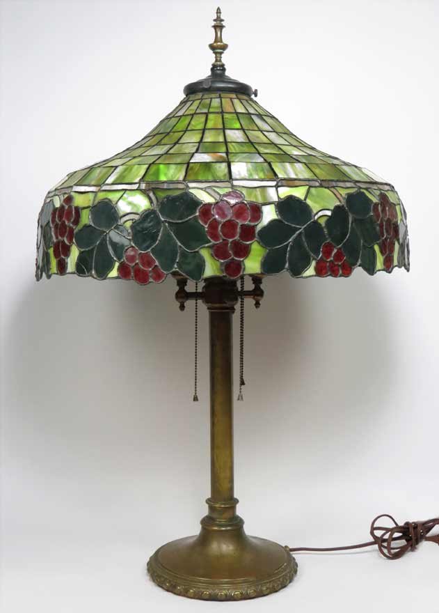 LARGE LEADED GLASS TABLE LAMP: green glass with grape border, 22” diam., four light sockets, on metal base, unsigned, 36” total h Ex. Kurt Reynolds collection, Boston