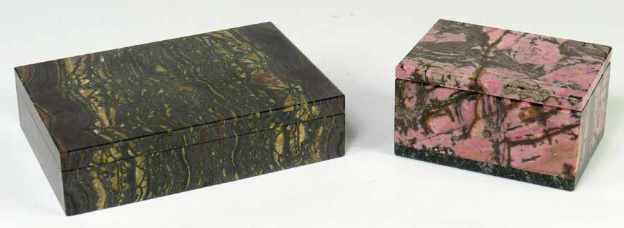 (2) STONE TRINKET BOXES: one a hinged tigerseye box with interior of gray and pink marble, 1.5”h; 6”w; 4”d; the other a rhodinite hinged box with black marble bottom, 2”h; 4”w; 2.75”d Ex. Kurt Reynolds collection,