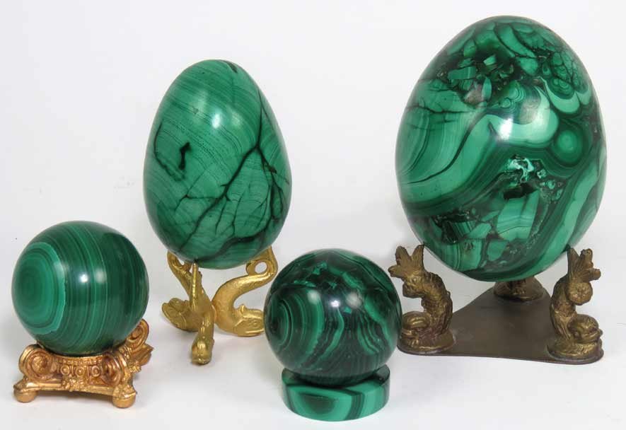 (on 4) MALACHITE OBJECTS: a large and a smaller egg, on brass stands; along with two small balls, one on brass stand, one with malachite base