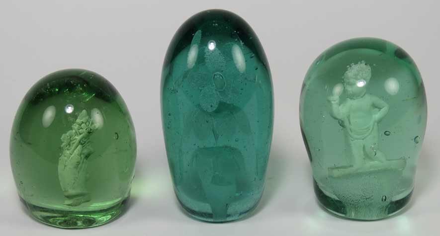 (3) GREEN GLASS ‘END-OF-DAY’ PAPERWEIGHTS: 19th c., one with flowers in a vase, 5.5”h; one with standing putto 4.5”h; the third, a hand holding flowers, 4”h Ex. Kurt Reynolds collection, Boston These paperweights, sometimes referred to a