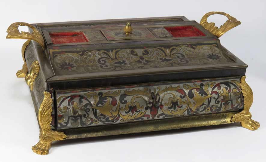 FRENCH CHARLES X TORTOISE AND BOULLE INKSTAND: overall scarlet tortoiseshell scrolls and cut-brass monkey and bird inlay, convex drawer; mounted ormolu masque to each side, ormolu leaf-form handles and claw feet, 7”h; 19.5”w (incl. handles); 1