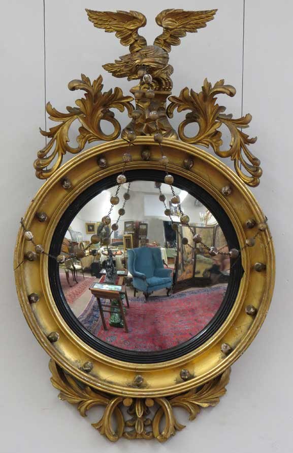 LARGE CLASSICAL GILDED CONVEX MIRROR: eagle with out-stretched wings standing on rocks, holding gilt ball and wire swags in beak, 37”h; 23”diam.