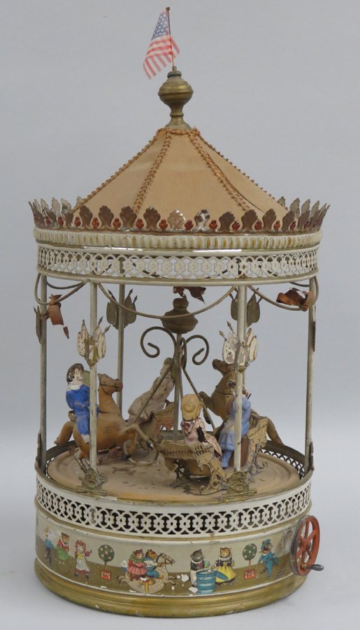 19TH C. TIN MUSICAL CAROUSEL: in working order, cloth top (one panel has split) with brass finial, two horses, one with boy rider (foot missing; the other rider missing), pulling a sled with two girl figures in each (some cracks i