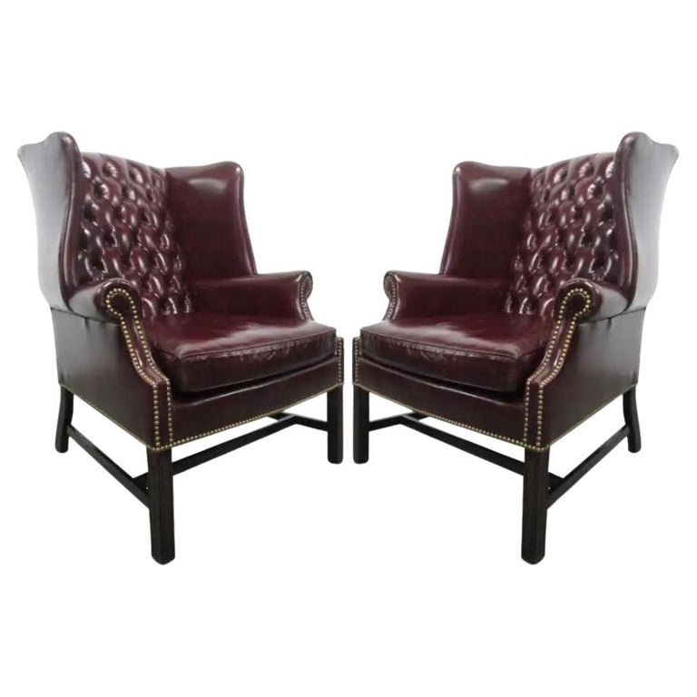 Vintage Leather Tufted Wingback Chairs: Burgundy leather tufted wingback chairs. Has brass studs, "H" wood stretcher and a loose cushioned seat. Measures: 42H x 34W x 32D.