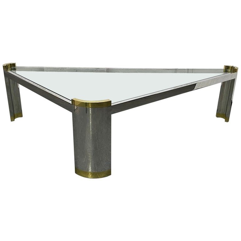 Ron Seff Chrome and Brass Coffee Table: Chrome and brass triangular coffee table by Ron Seff. The legs of the table have brass tops, brass bases with a thick glass top. Karl Springer style. Measures: 18H x 73.5W x 37.5D.