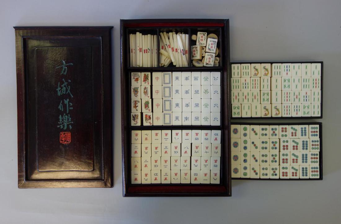 Mahjong Set with Rosewood Case: A Mahjong set with rosewood case. Complete set of tiles with betting sticks and dice. The tiles colorfully stamped on white plastic to simulate bone, dovetailed bamboo wood backs. The dovetailed case 