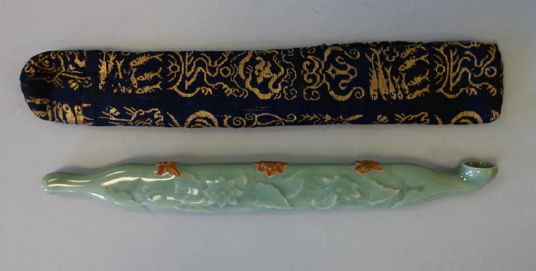 Japanese Celadon Porcelain Kiseru Pipe & Pouch: A Japanese celadon porcelain Kiseru tobacco pipe. The pipe decorated with a raised white glazed flower motif. The top decorated with a flower between two butterflies. Measures 8-1/8" long, 1" high, 7/