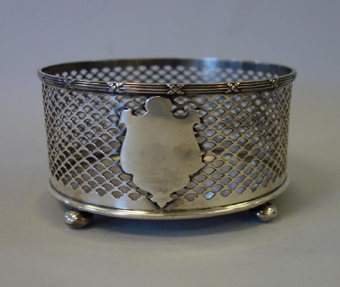 Meriden Brittania Sterling Wine Champagne Coaster: An American sterling silver wine / champagne coaster by Meriden Brittania Co. Open-work cage motif, central shield, four ball feet. Measures 5.25" diameter, 2.75" high. Weighs 6.5 troy oz (197.4 grams