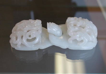 Chinese Carved White Jade 2-Piece Belt Hook: A Chinese carved white nephrite jade 2-piece belt hook / buckle, c.1800 Qing Dynasty. Finely carved with dragon head terminal and hydra / chilong cavorting among stylized clouds. Measures 4-5/8" long,