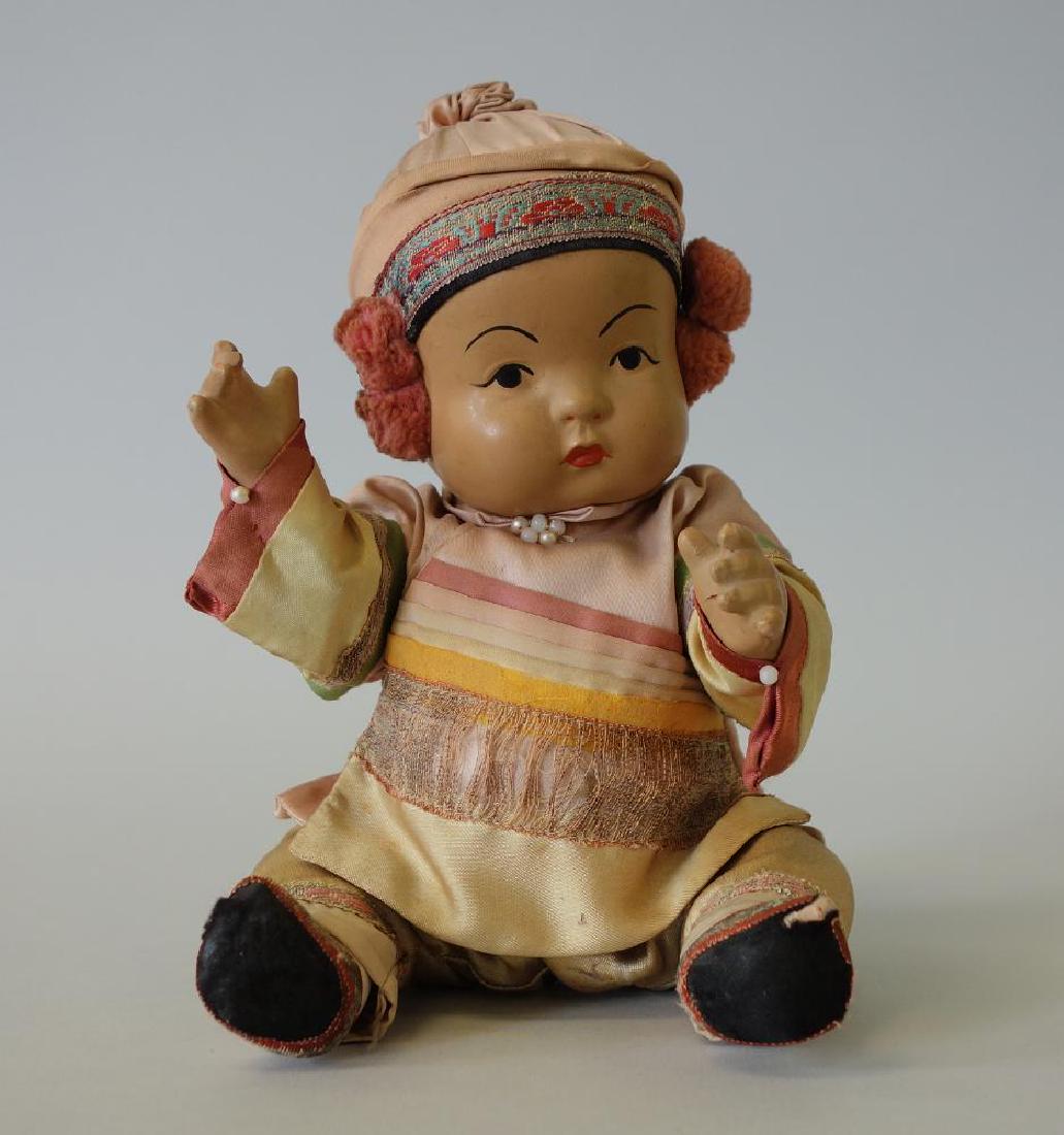 Chinese Bisque Doll in Silk Clothing: A bisque doll. The doll depicts a young girl dressed in a silk tunic with pants. Sitting measurement 8" high, 5" wide, 4" deep.