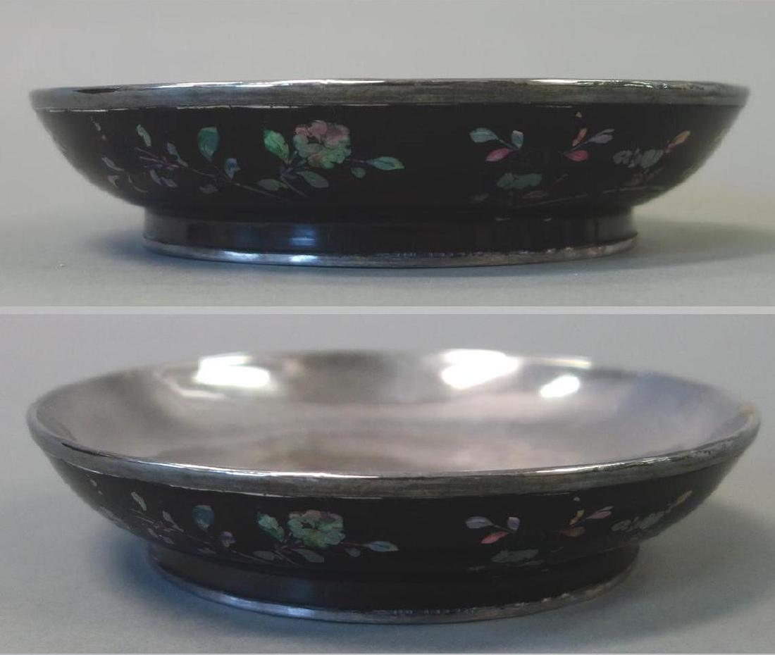 Chinese Lacquer on Silver Bowl, Abalone Inlay: A Chinese black lacquer shallow bowl. Floral decorated with mother of pearl / abalone inlay. Silver interior lining and silver rimmed foot. Measures 7" diameter, 1.5" high.