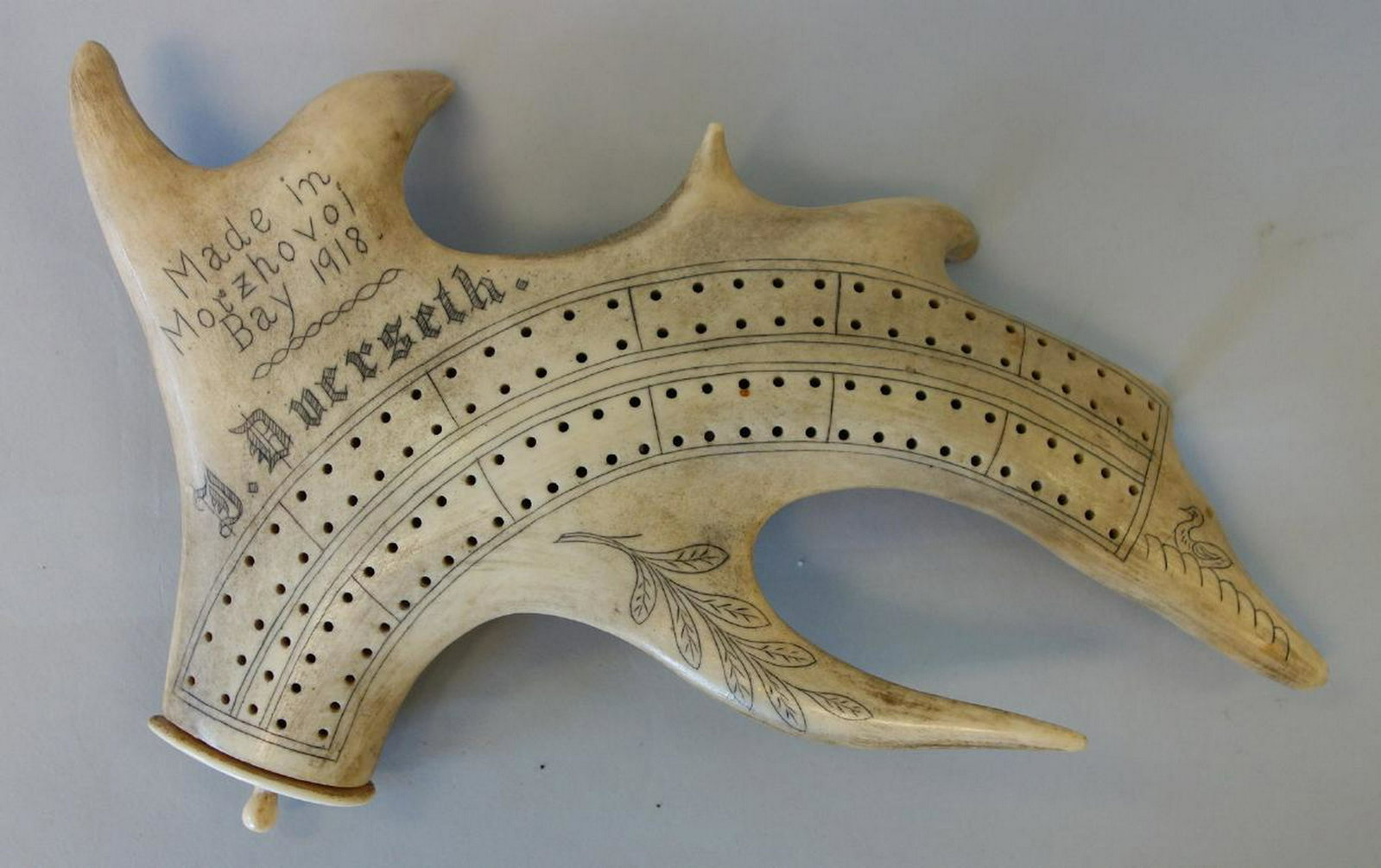 Morzhovoi Bay, 1918 Moose Antler Cribbage Board: An antique moose antler cribbage board. Scrimshaw decoration with a duck and leaves. Made in Morzhovoi Bay, Alaska, 1918. Artist / carver signed, J. Duerseth. The four pegs housed within the antler an
