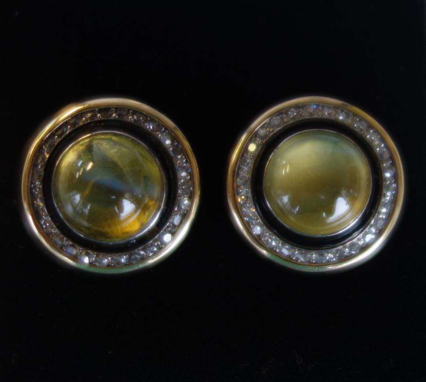 Diamond & Cat's Eye 14K Gold Earrings: A pair of diamond and cat's eye 14K gold earrings. The 14K yellow gold earrings, each centered with a round cabochon cat's eye stone having an approximate carat weight of 5.0.cts each and surrounded b