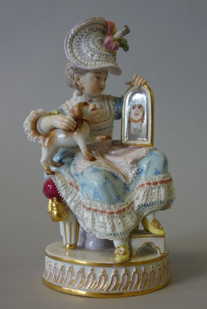 Meissen Porcelain Figurine, Girl With Dog & Mirror: A fine Meissen porcelain figurine / figural group depicting a young woman holding her dog in her lap and holding a mirror showing the dog's reflection. Signed underfoot with the Crossed Swords mark. I