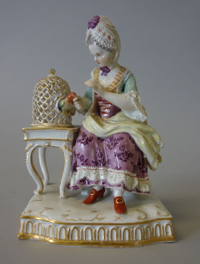 Meissen Porcelain Figurine Touch, Girl & Bird Cage: A fine Meissen porcelain figurine / figural group. From the Senses set. Titled "Touch", depicting a young woman feeding her bird, which peers out of a birdcage resting on a table. Modeled by Johann Ca