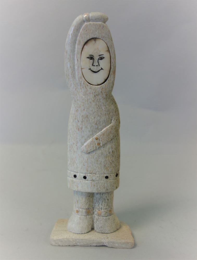 Leonard Olanna (20thc Alaska) Inuit Eskimo Carving: An Inuit Eskimo carving by Leonard Olanna (20thc Alaska). The petrified whale bone carved to depict an Eskimo figure wearing a Yupik parka. Scrimshawed walrus tusk face. Artist signed on the underside