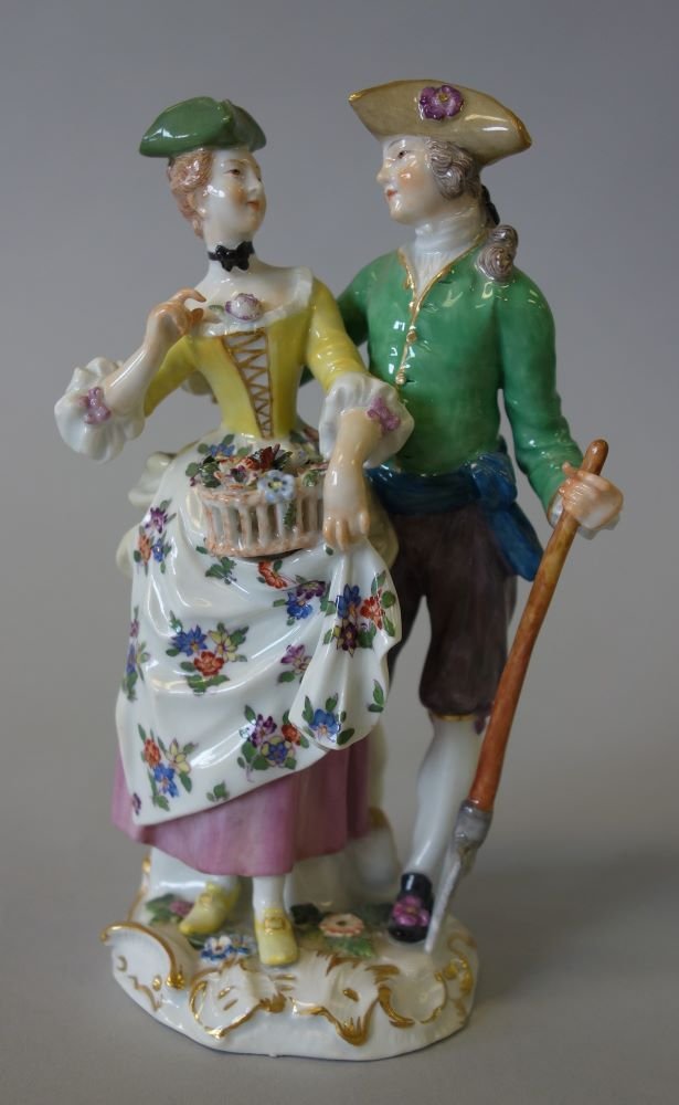 Meissen Porcelain Figural Group, The Gardeners: A fine Meissen porcelain figurine / figural group depicting a young man and woman in period costume, both wearing a tri-corner hat. The woman holds a basket of flowers and the man holds a shovel, "The