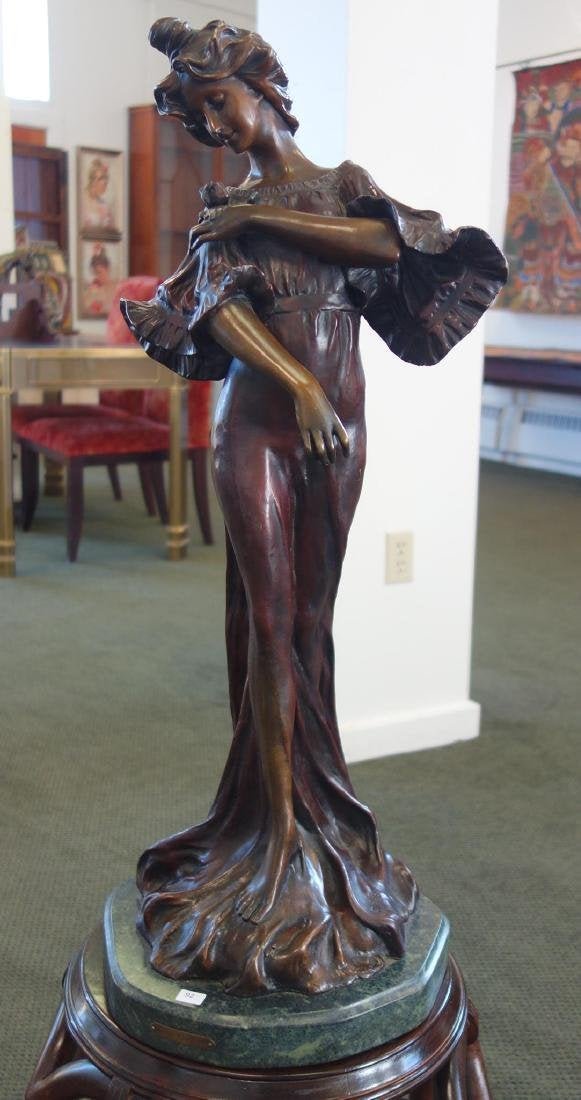 Francisco Flora (b-1857) Bronze "Iris" c.1900: A solid bronze sculpture by Francisco Flora (b-1857, active in Spain). The large sculpture depicts a young female in a long flowing gown admiring her floral corsage. Titled: Iris, c.1900. Signed F. Fl
