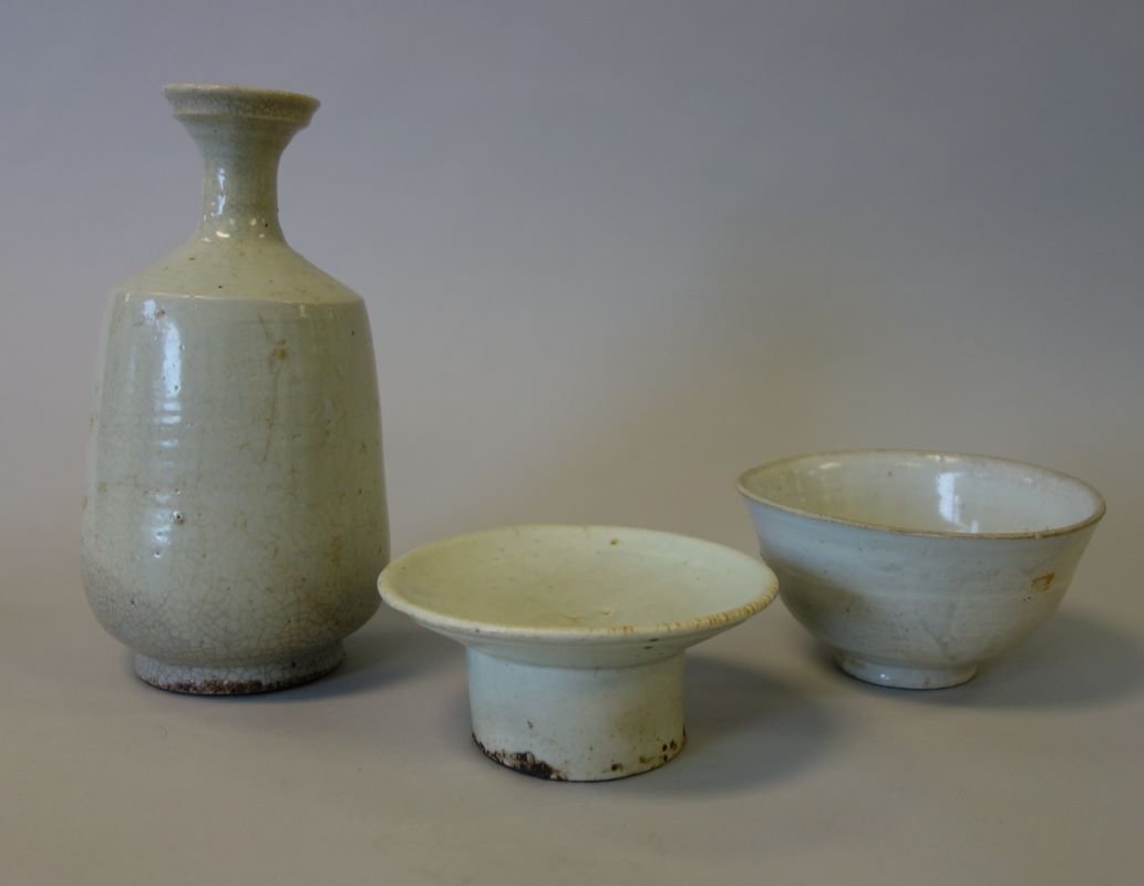 3 Korean Porcelain Objects, Yi Dynasty: Korean porcelain, Yi Dynasty. Comprised of a Korean porcelain bottle formed vase, light celadon crackle glaze over a horizontal ribbed body. Measures 9.5" high, 5" diameter at the widest point on the 