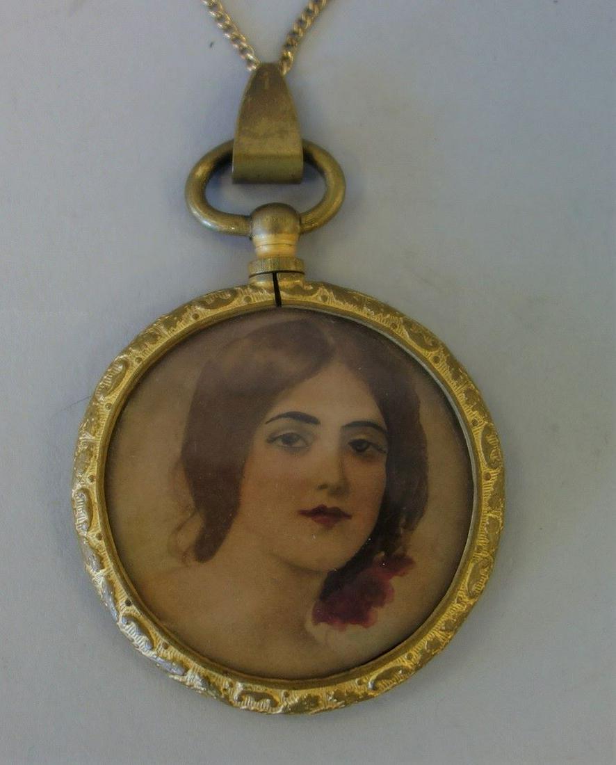 Portrait Miniature of a Lady - Pendant Necklace: A portrait miniature of a lovely young woman. The portrait is housed under glass in a gilt metal frame and fashioned as a pendant necklace with bail and chain. The portrait measures 1.75" diameter (in