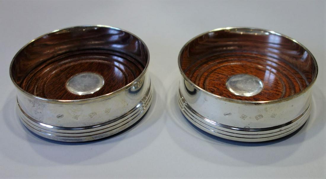English Sterling & Mahogany Wine Coasters: A pair of English sterling silver and mahogany wine coasters. Both hallmarked for Broadway & Co, Birmingham, England, 1988. Each measuring 3.5" diameter, 1.25" high.