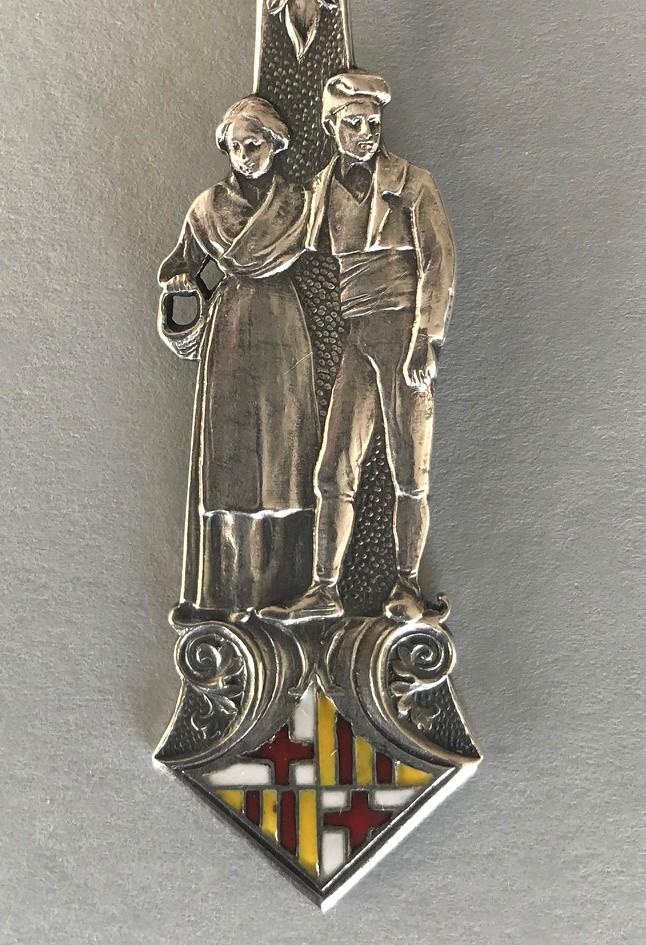 Masriera LBB Silver & Enamel Spoon, Barcelona: A Spanish silver and enamel spoon, Signed Masriera, LBB (Barcelona, Spain) and with the hallmark indicating .916 silver purity. The spoon depicts a man and a woman surmounting an enameled Spanish hera