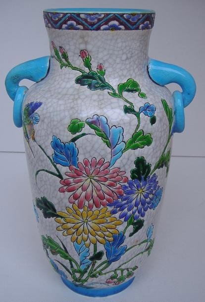 Longwy French Faience Enameled Vase: Well decorated with a bird among an abundance of florals. Repair to handle, crazing and a large hole on the underside for conversion to a lamp base. Height: 10.5 inches.