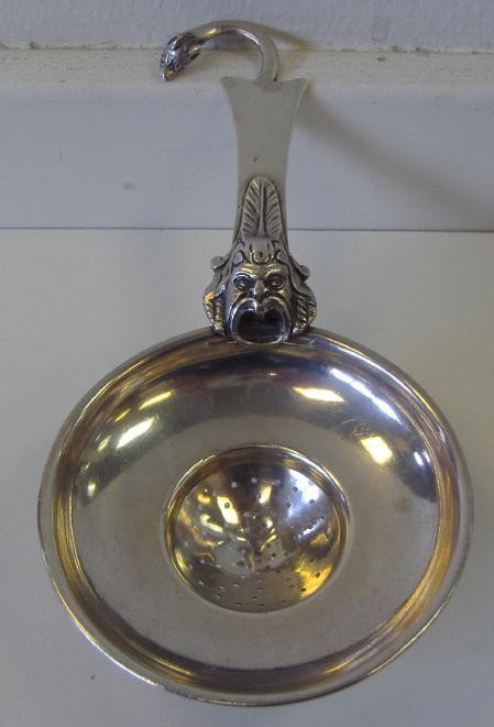 Italian Silver Strainer with Bocca della Verita: The strainer is decorated with the Bocca della Verità; The Mouth of Truth. Starting from the Middle Ages, it was believed that if one told a lie with one's hand in the mouth of the sculpture, it woul